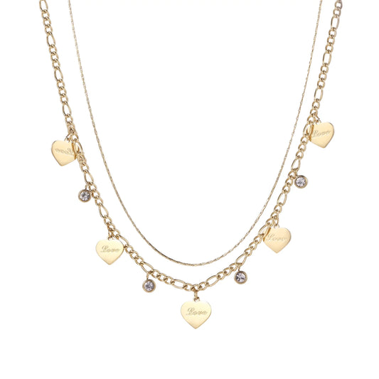 Gold layered necklace set with engraved heart pendants and crystal accents on cream background